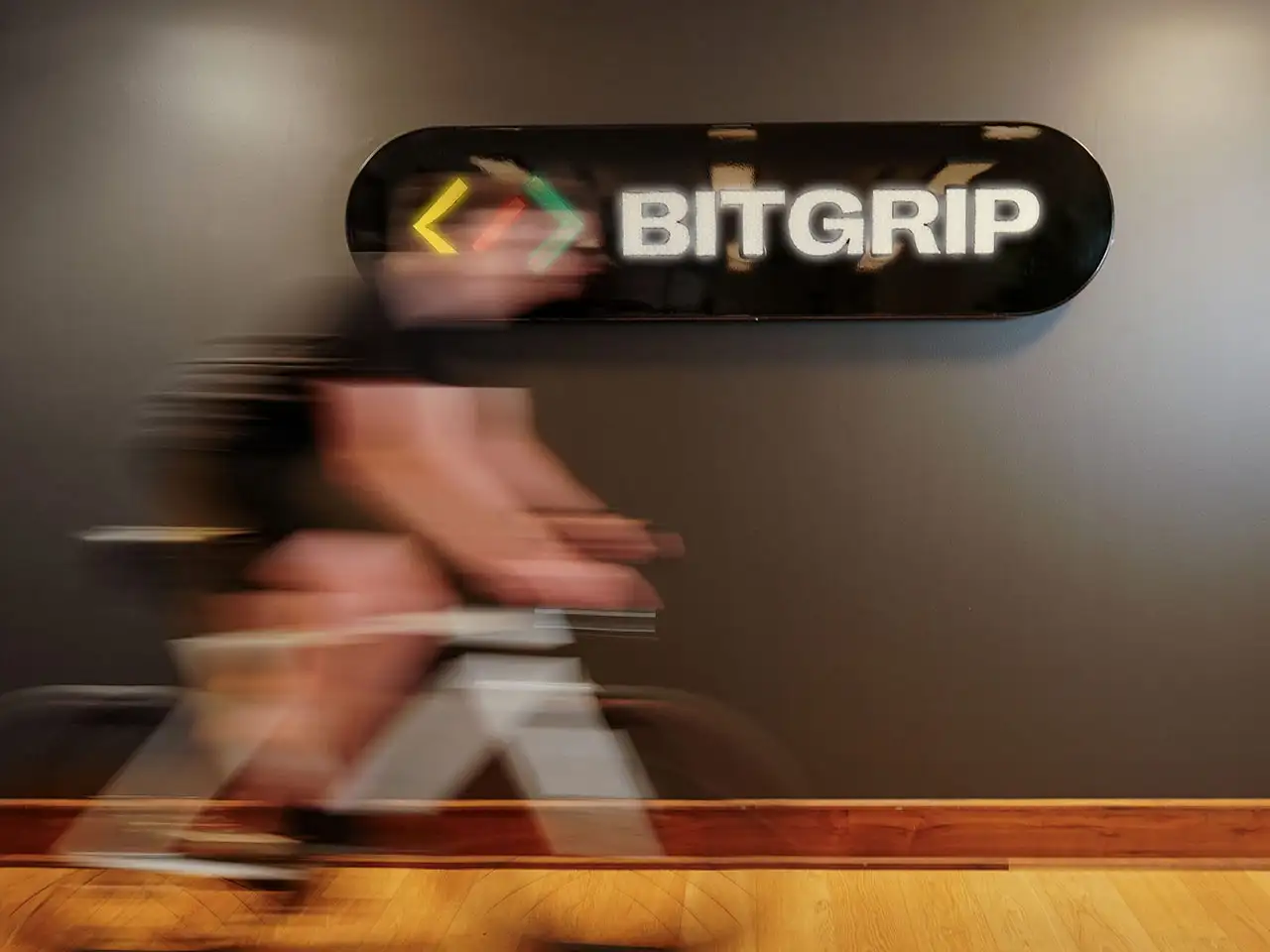 Im Büro von IT-Dienstleister und JobRad-Arbeitgeber BitGrip fährt ein Mitarbeiter vor dem Unternehmens-Logo mit leichter Bewegungsunschärfe.