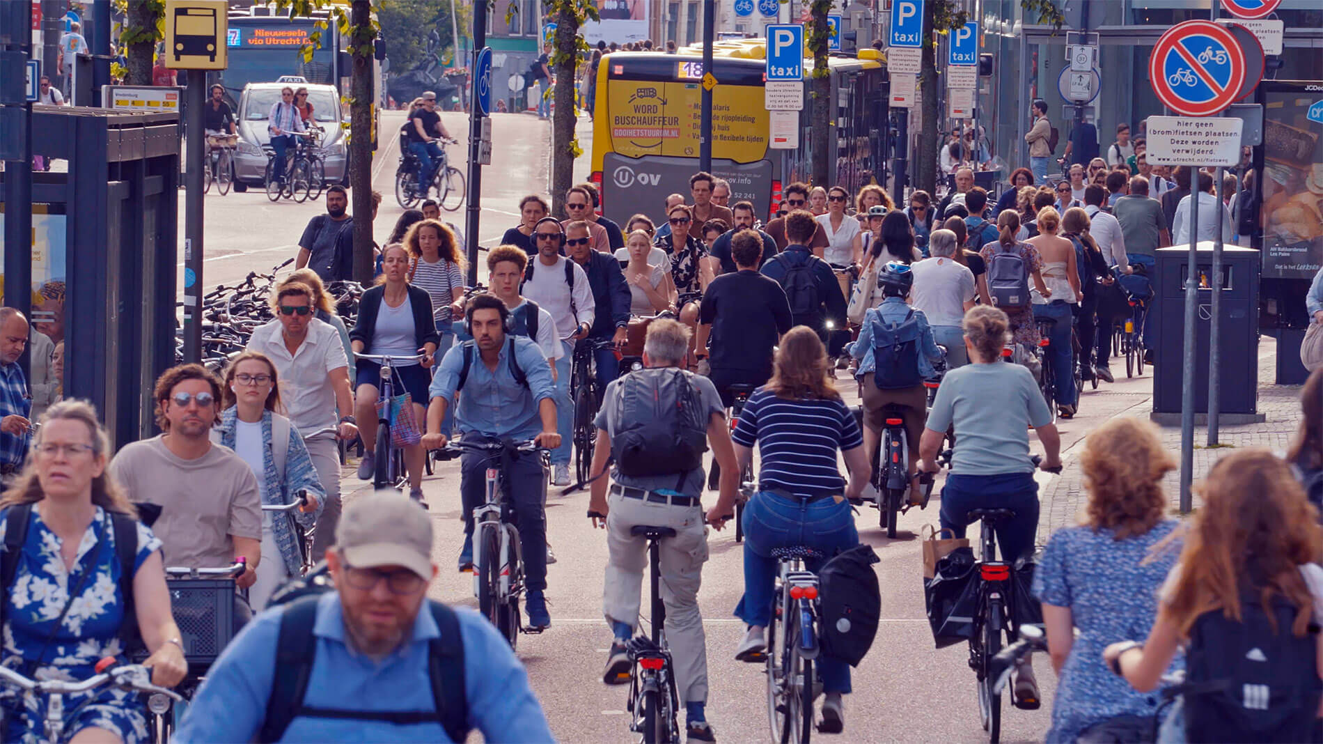 Der Vekehr in Utrecht: unzählige Menschen auf Fahrrädern, im Hintergrund ein Auto und ein Bus.